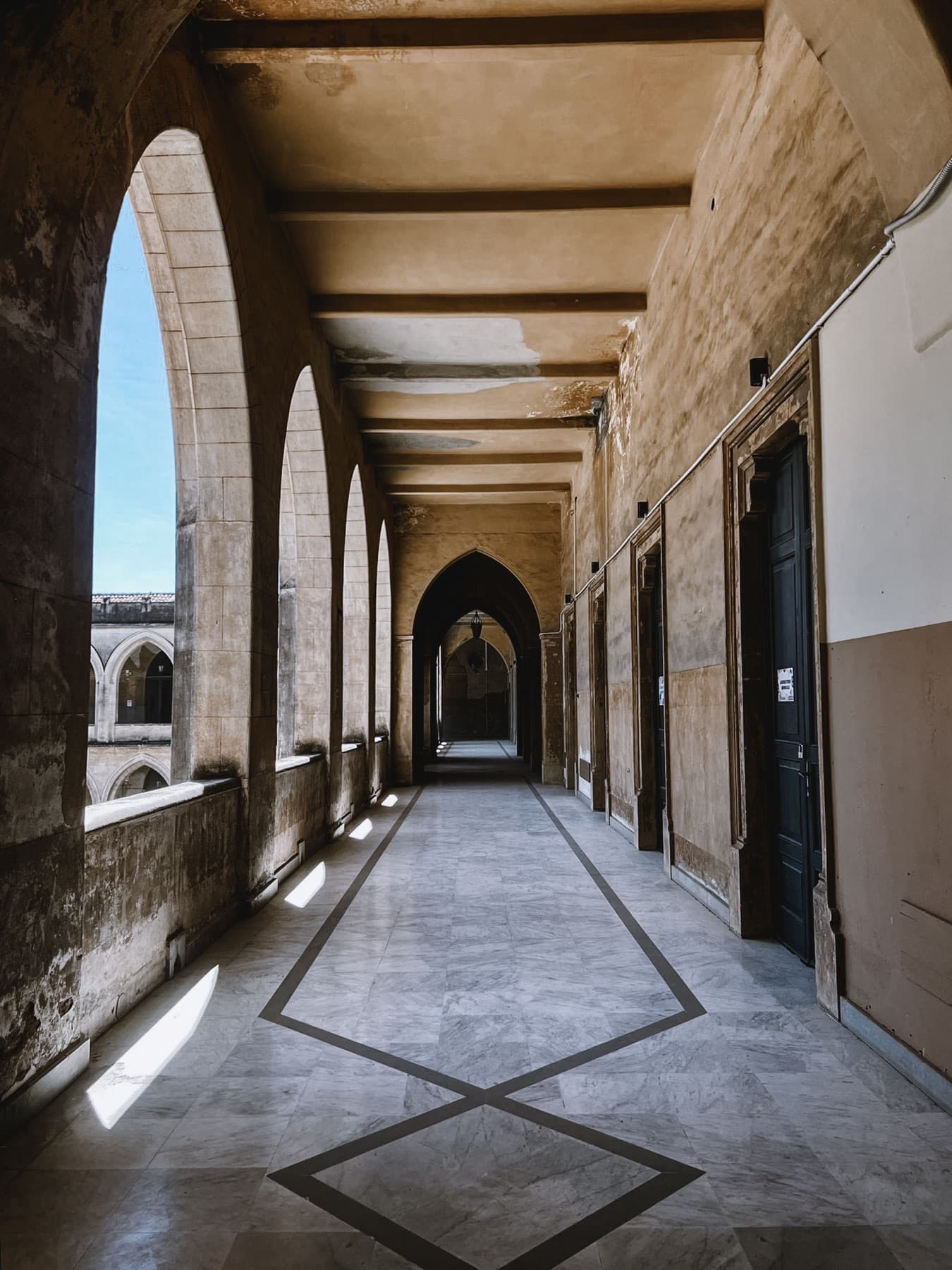 A sunlit arched corridor running along the cloister.
