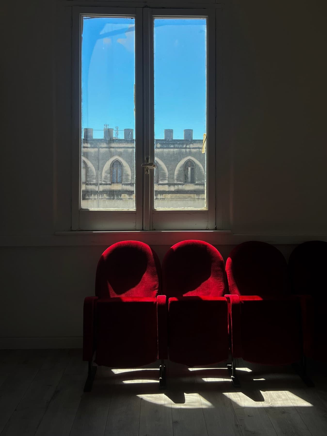 Red velvet chairs beside a tall window overlooking the cloister.