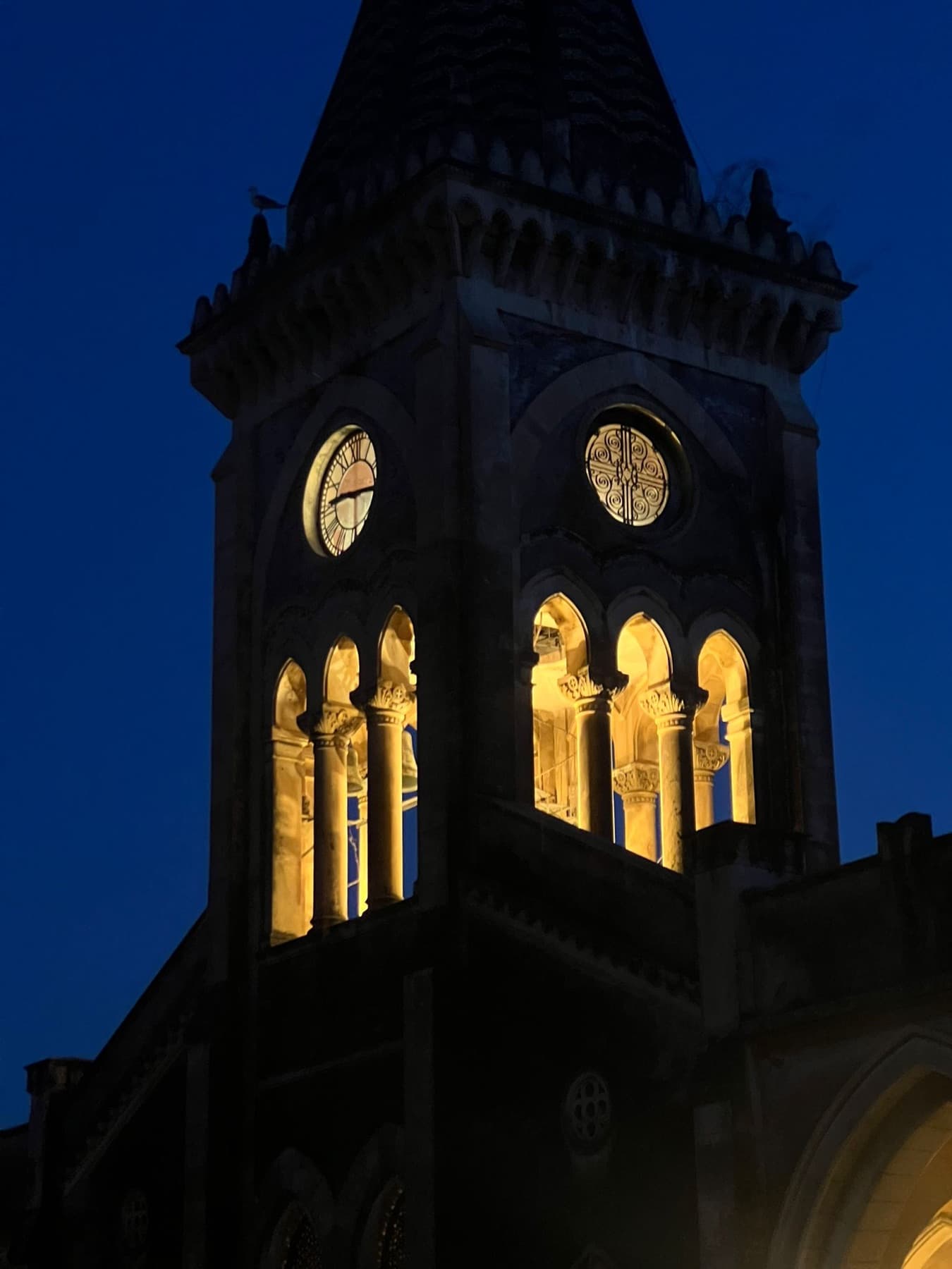 The illuminated clock tower of the Istituto dei Ciechi in Catania at night.